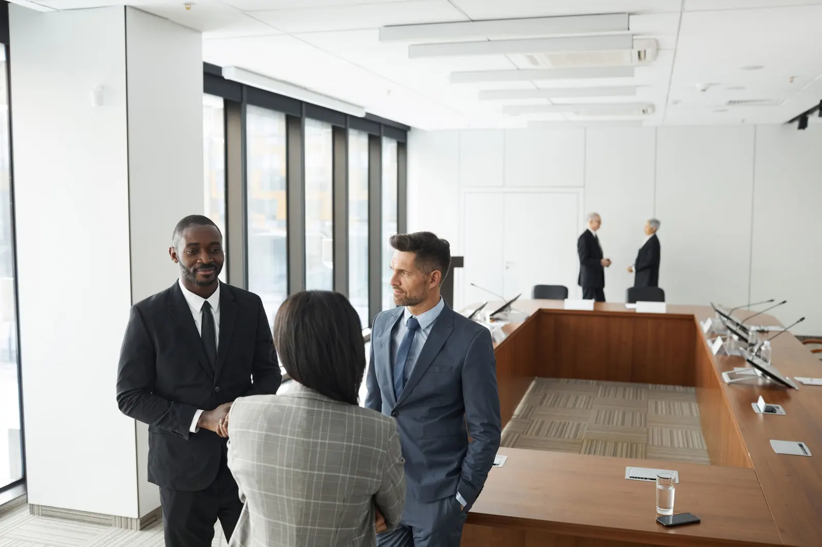 Trois professionnels discutent debout dans une salle de conseil